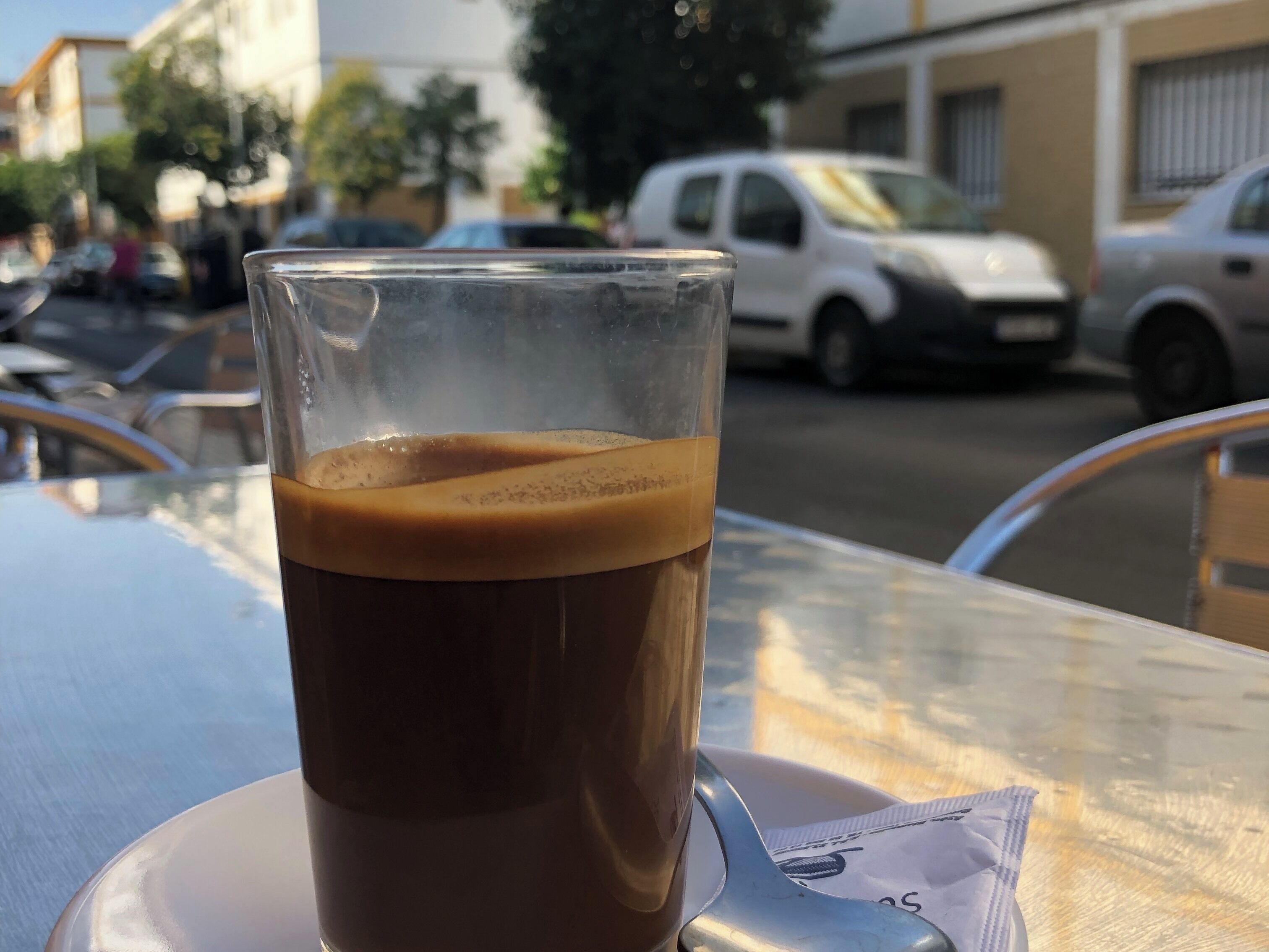 A glass of iced coffee on a table with a spoon and a napkin.