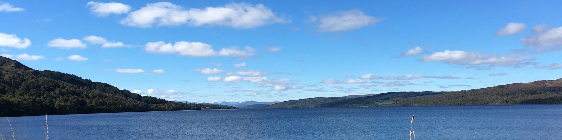 A calm lake surrounded by hills and sparse vegetation.