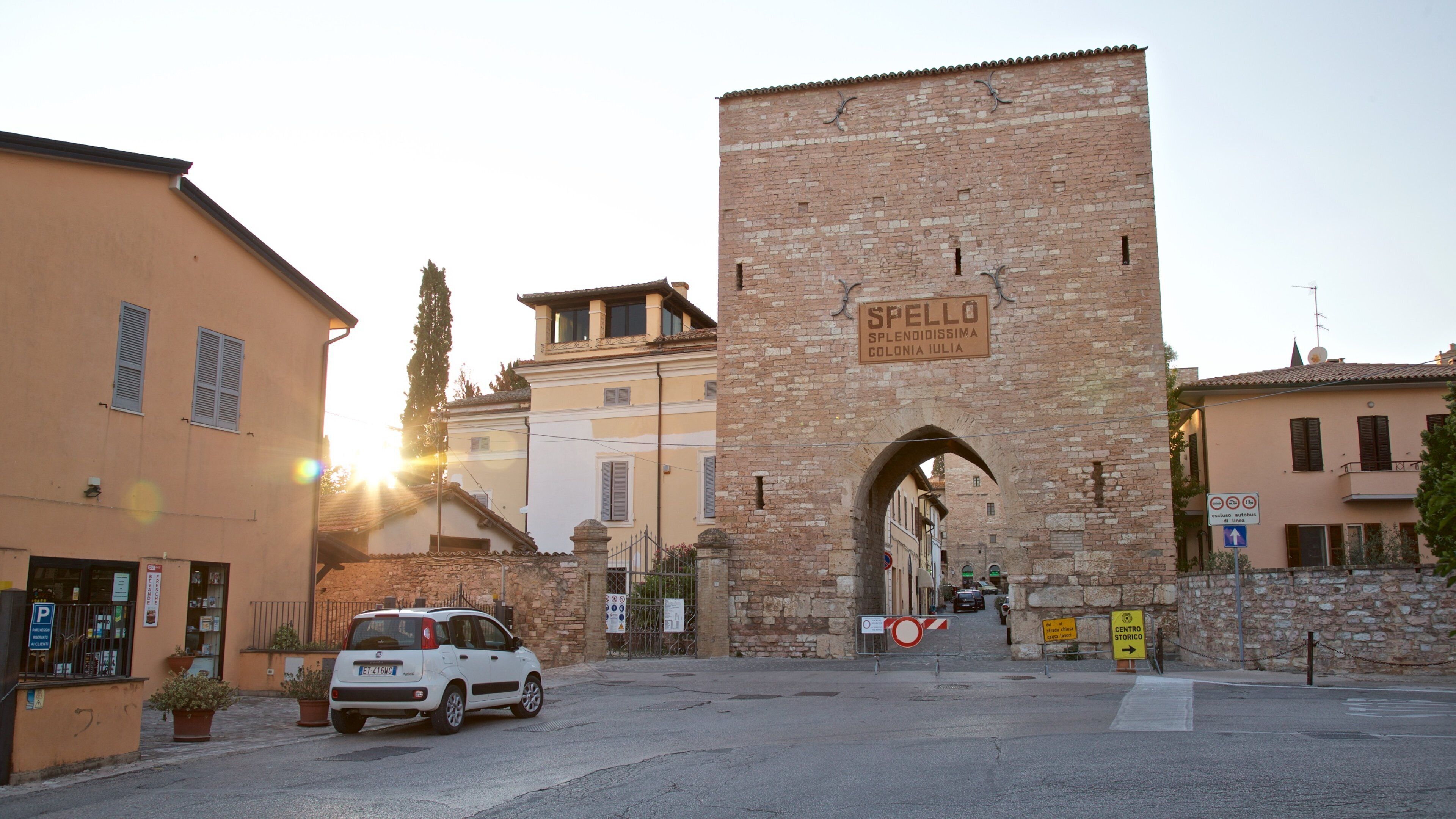 Un arco de piedra histórico con un letrero que dice 'SPELLO' y 'CIUDAD DE IULIA'.