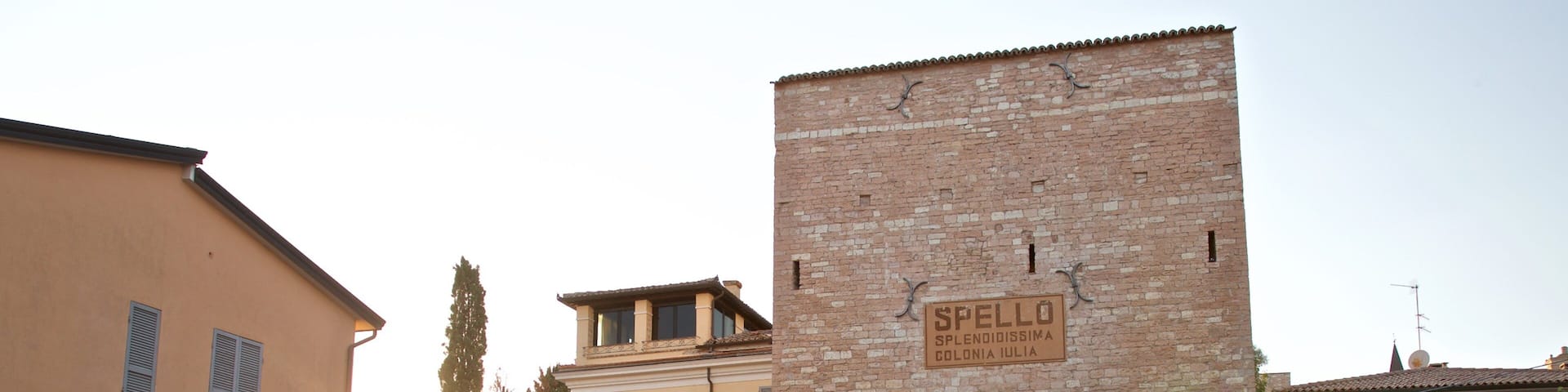 A historic stone archway with a sign reading "SPELLO" and "CITTA DI IULIA".