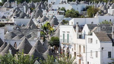 Un pueblo con edificios blancos y techos cónicos, rodeado de árboles y un paisaje montañoso.