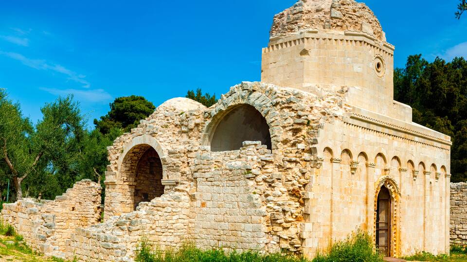 An ancient stone structure with arched doorways and a dome.