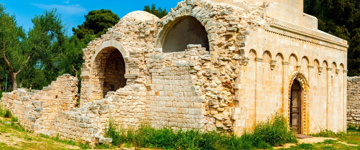 An ancient stone structure with arched doorways and a dome.