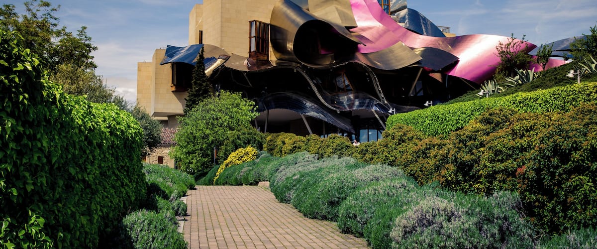 A modern architectural structure with metallic surfaces and a pathway leading to it.