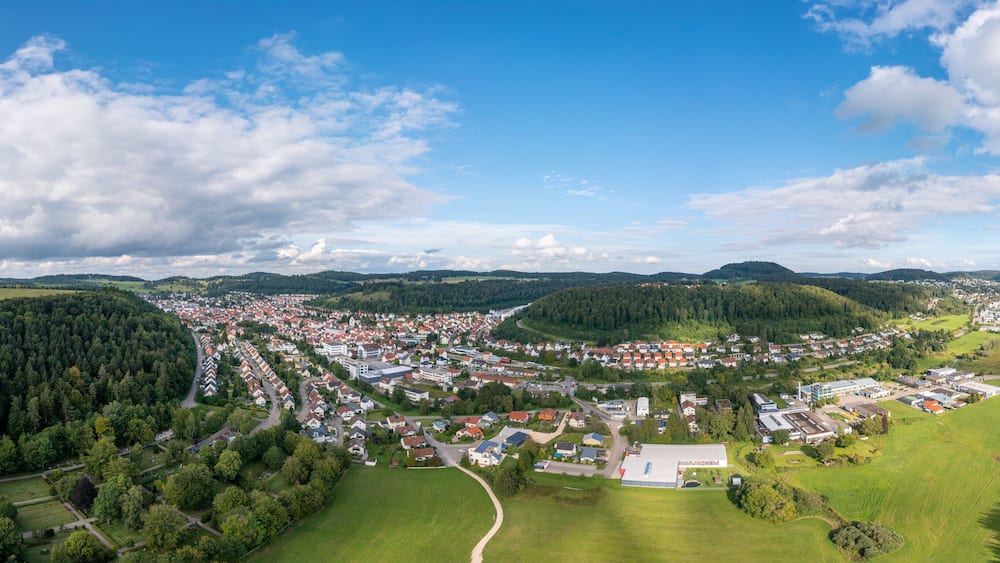 An aerial view of a town surrounded by forests and hills.