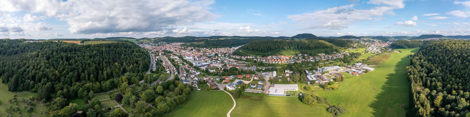 An aerial view of a town surrounded by forests and hills.