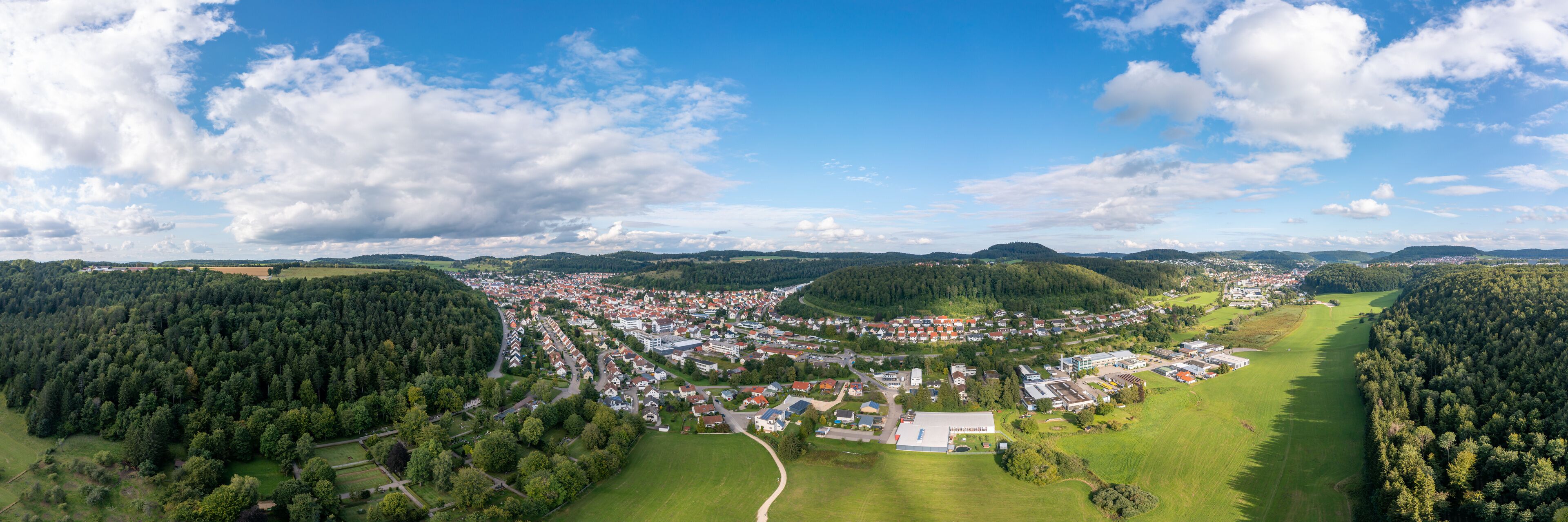 An aerial view of a town surrounded by forests and hills.