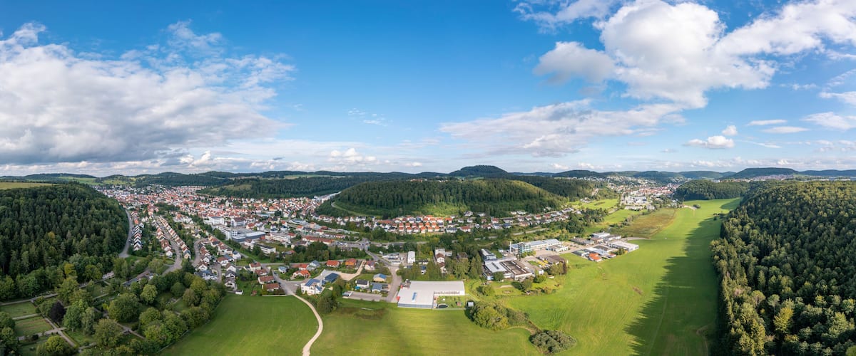 An aerial view of a town surrounded by forests and hills.