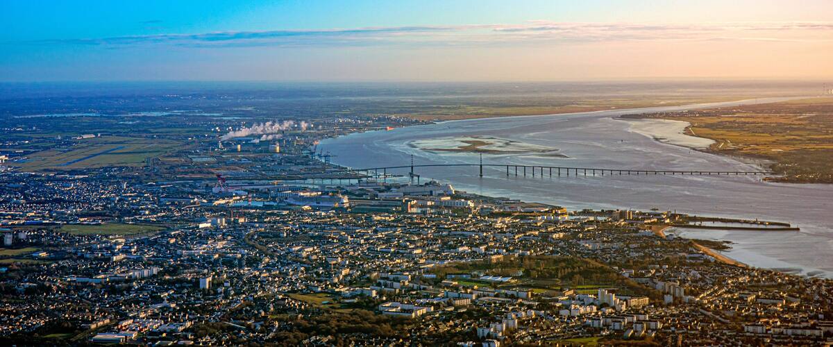 An aerial view of a coastal city with a bridge, industrial area, and residential zones.