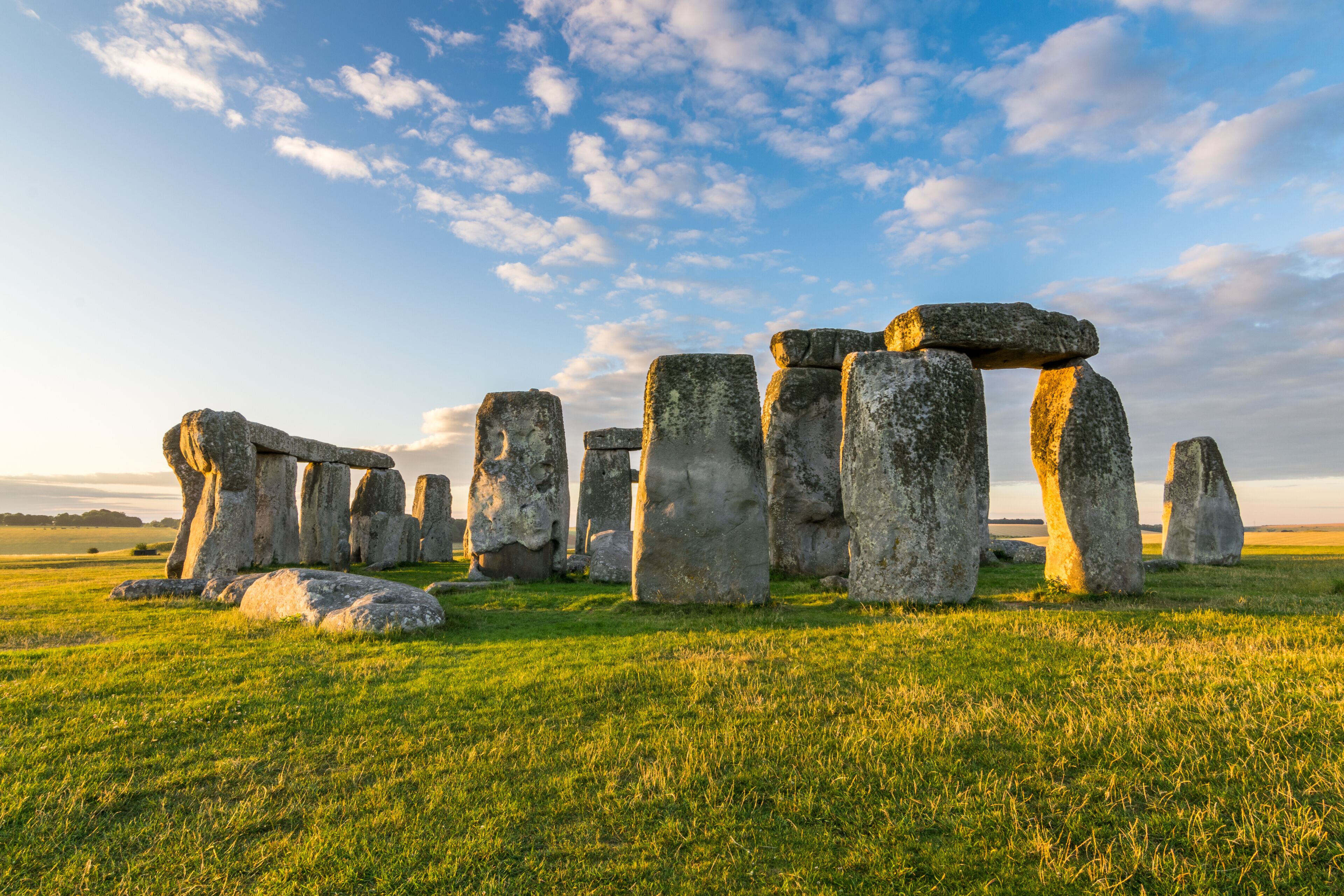 Stonehenge standing in a grassy field under a partly cloudy sky.