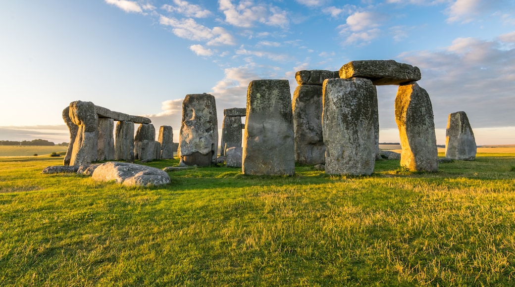Stonehenge standing in a grassy field under a partly cloudy sky.