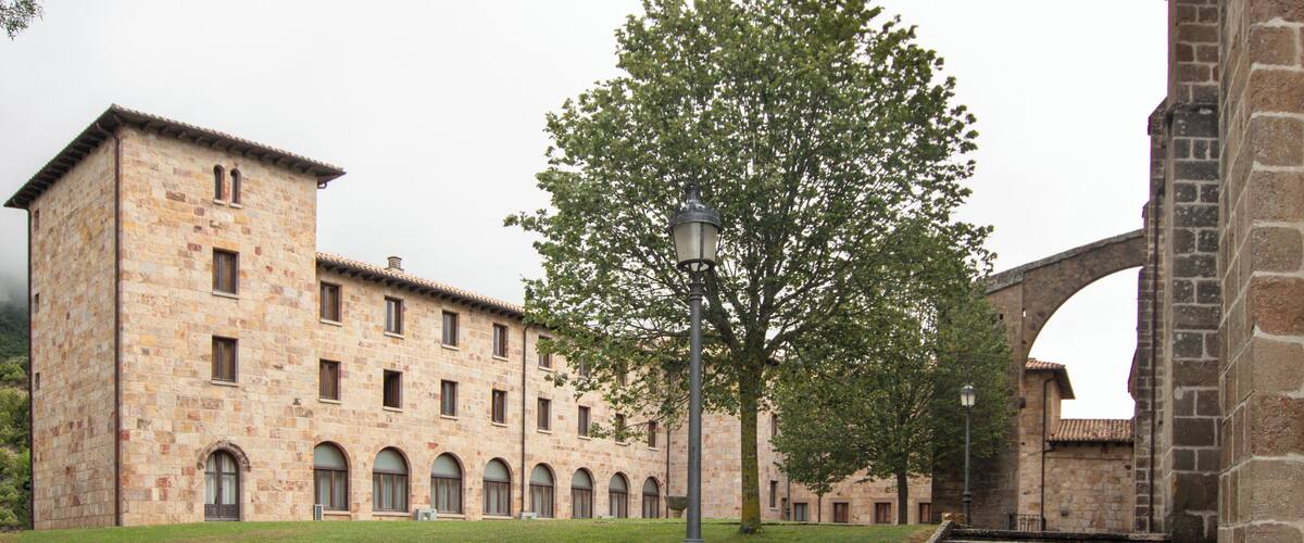 A stone building with arched windows and a tree in front.
