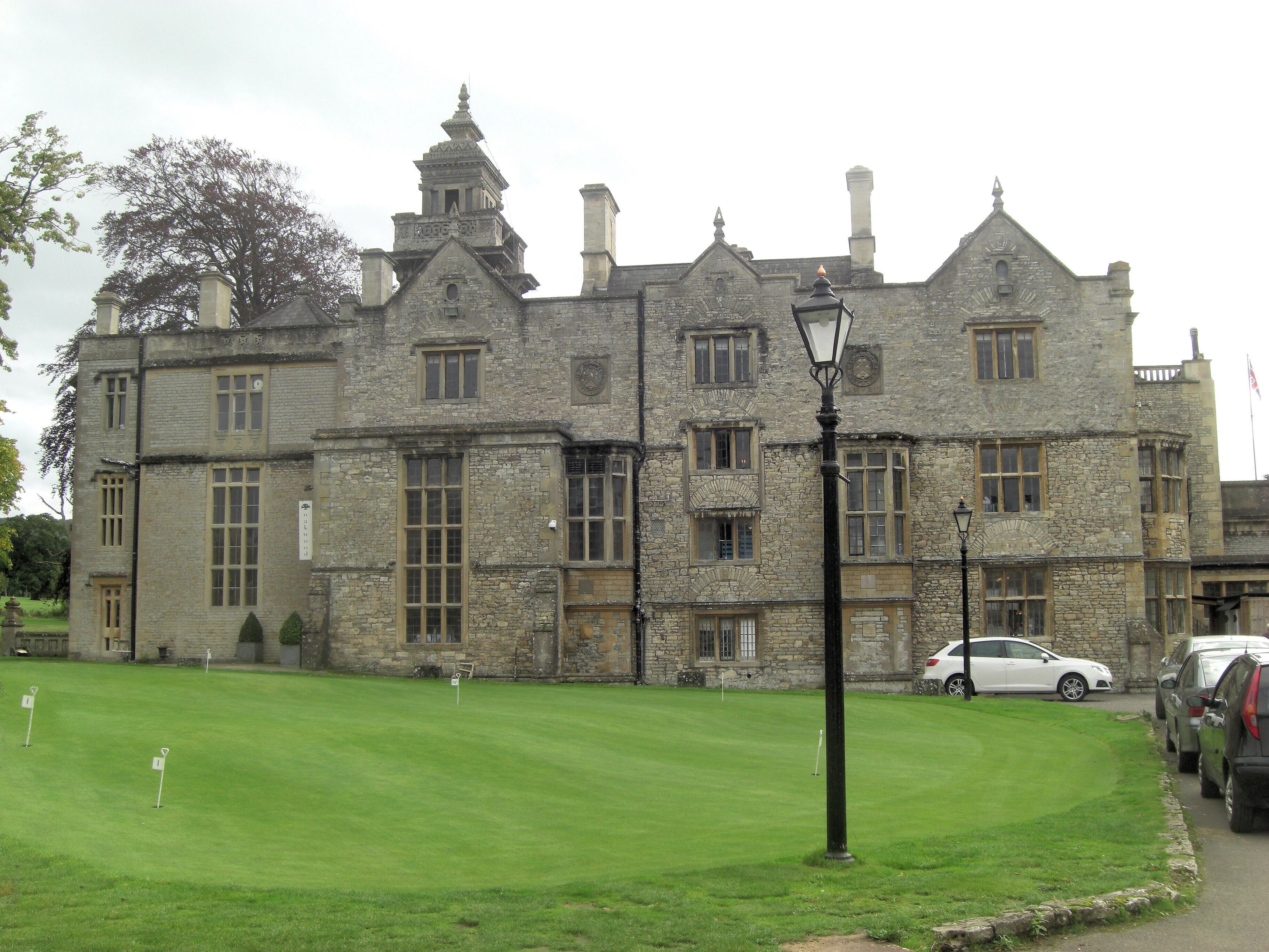 A historic stone building with multiple chimneys and a well-maintained lawn in front.