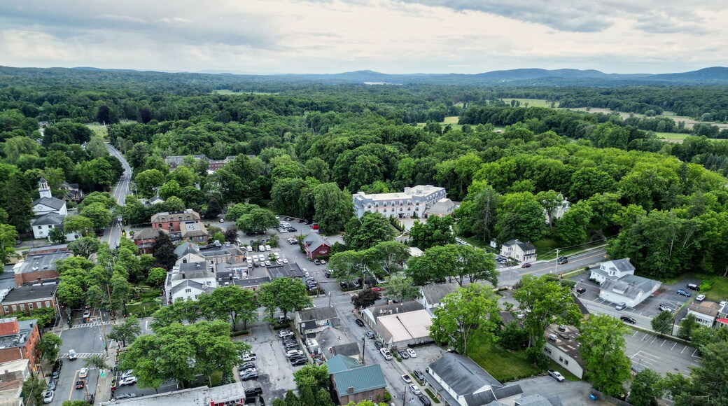 aerial view of rhinebeck new york (hudson valley small town next to catskill mountains) trees main street homes businesses houses (residential and commercial downtown area) drone looking down sunset