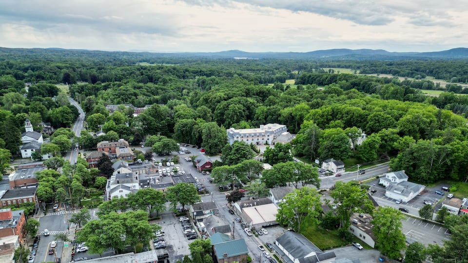 aerial view of rhinebeck new york (hudson valley small town next to catskill mountains) trees main street homes businesses houses (residential and commercial downtown area) drone looking down sunset