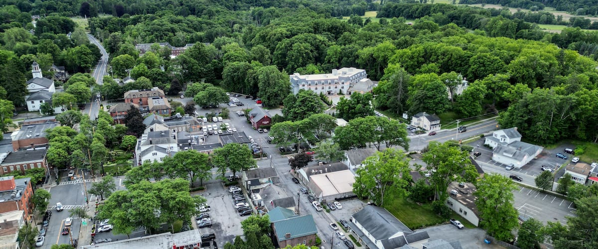 A town surrounded by lush green hills and a large white building.