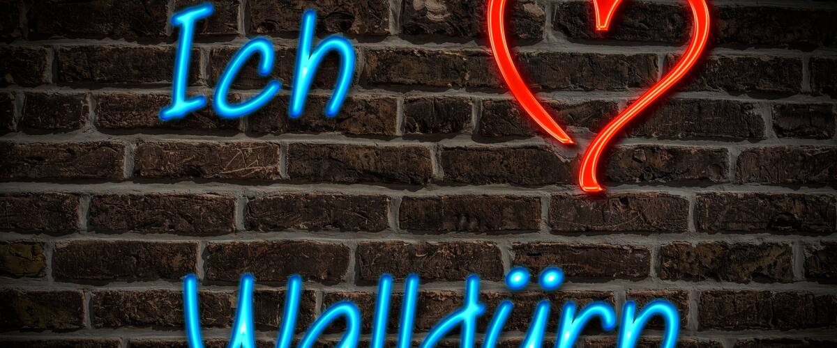 A neon sign with the text "Ich Walldörn" on a brick wall.