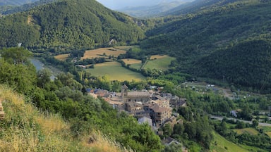Un valle con un río, rodeado de colinas y un pueblo pequeño con edificios históricos.