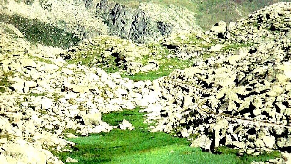 A mountainous landscape with a green valley and a winding road.