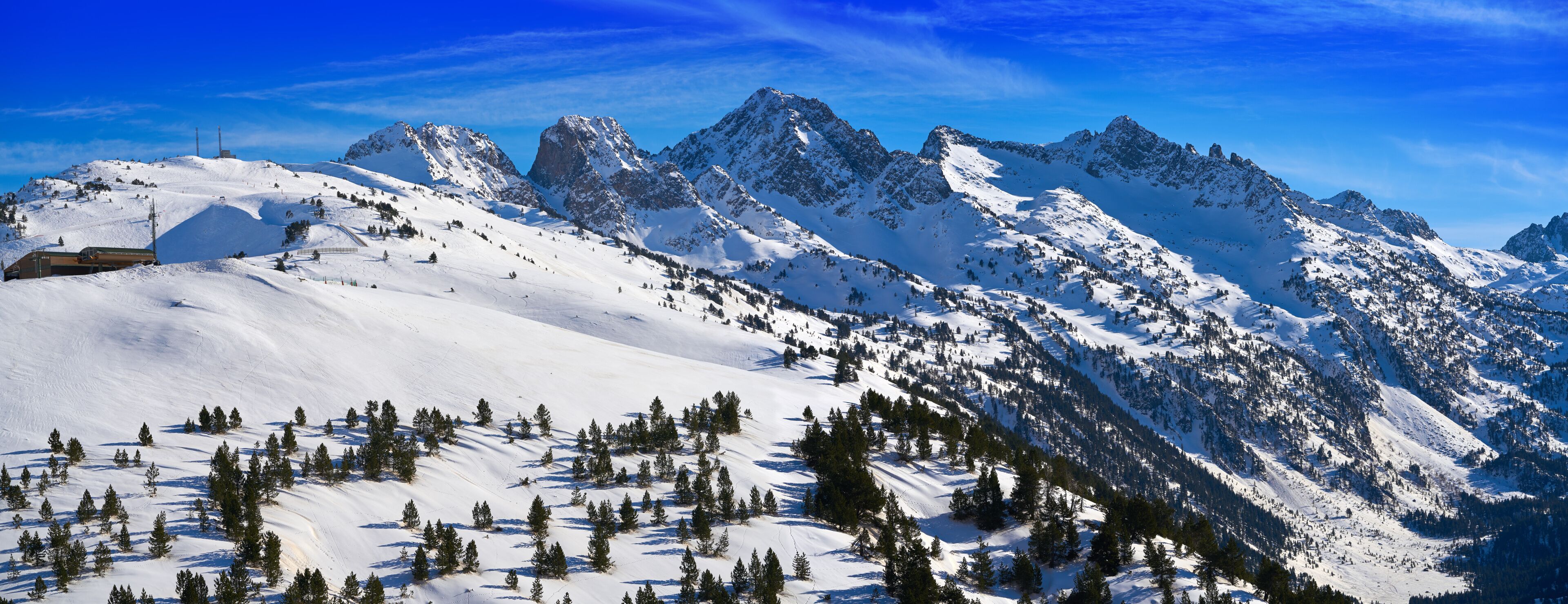 A snow-covered mountain range with a ski resort and a clear blue sky.