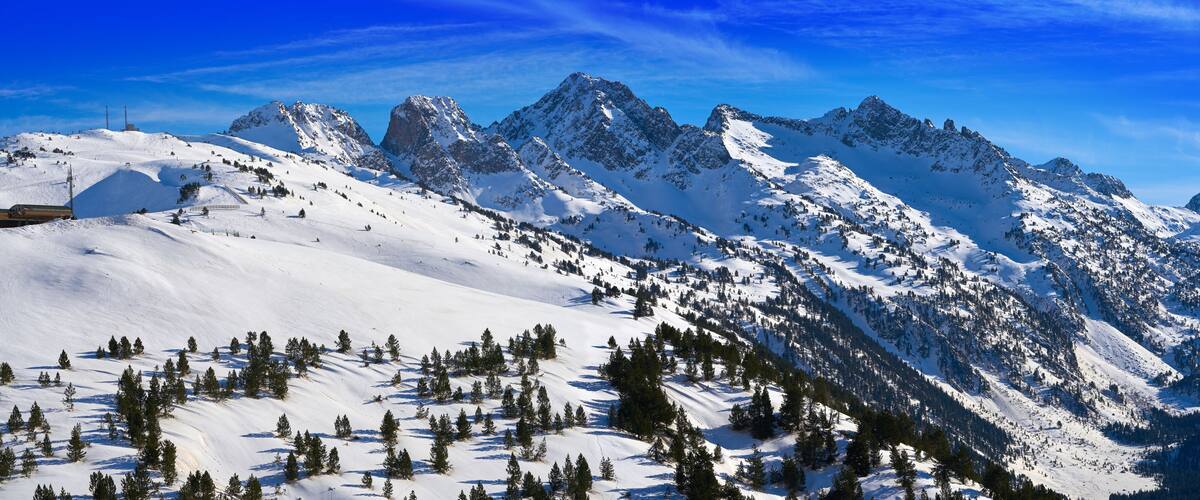 A snow-covered mountain range with a ski resort and a clear blue sky.