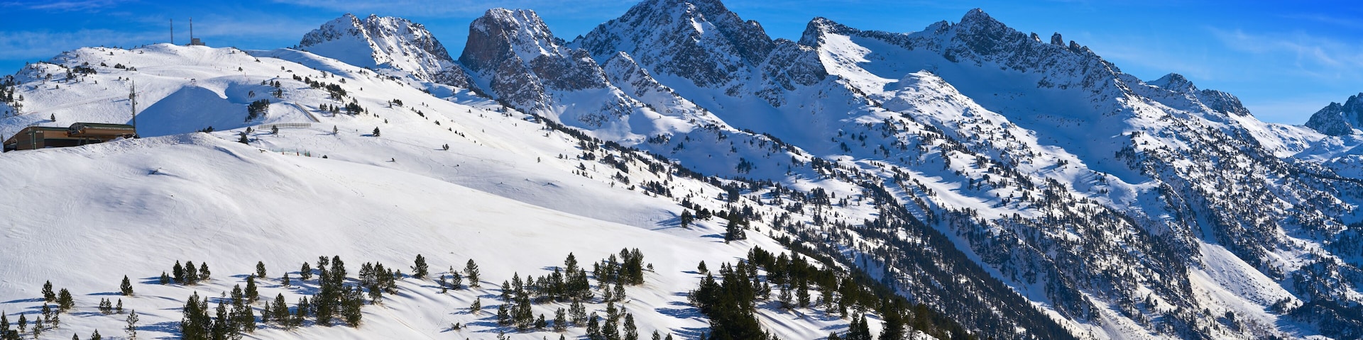A snow-covered mountain range with a ski resort and a clear blue sky.
