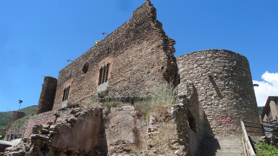 An ancient stone building with a large tower and a staircase leading up to it.