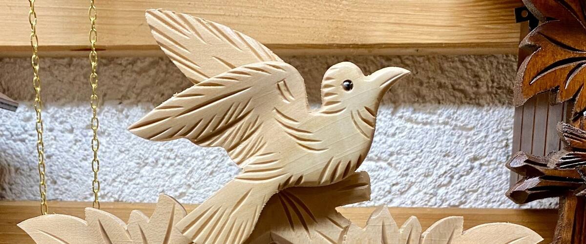 A wooden cuckoo clock with a bird and leaves design.