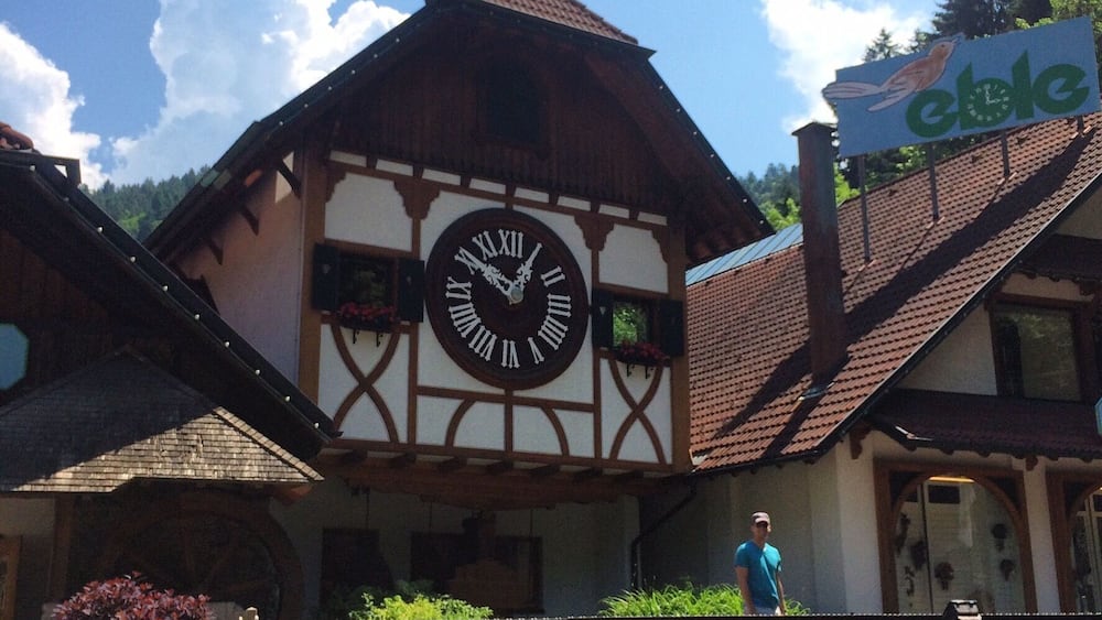 A traditional half-timbered building with a large clock, a weather vane, and a sign for 'eClé'.