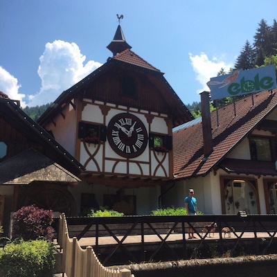Un edificio tradicional con entramado de madera, un gran reloj, una veleta y un letrero que dice 'eClé'.