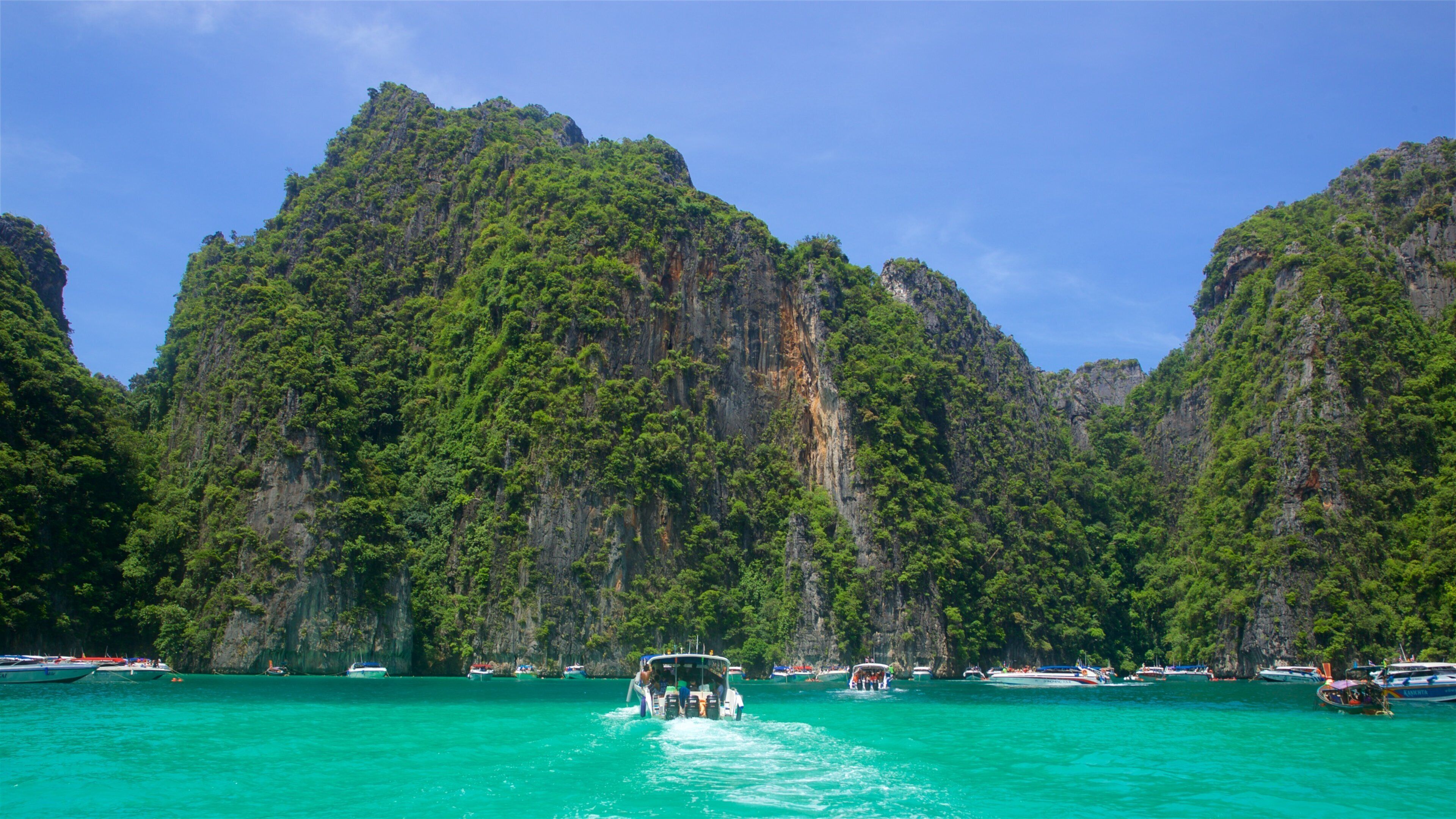 A boat on turquoise water with a mountainous backdrop.