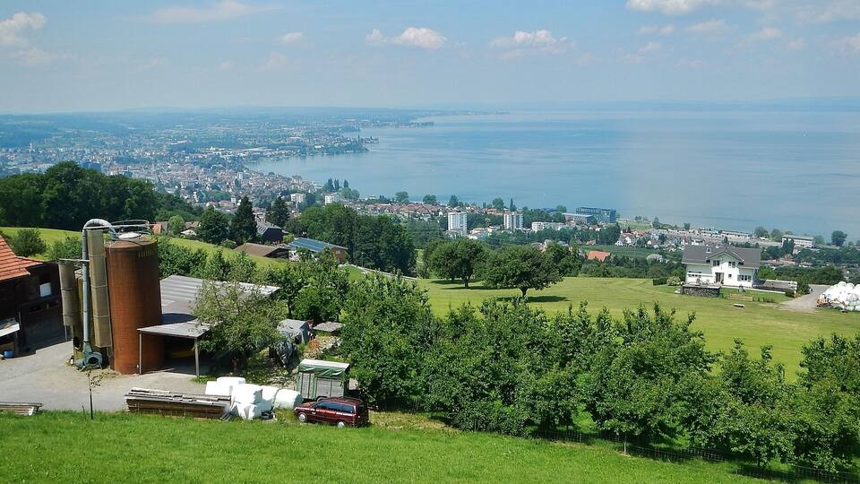 A scenic view of a town with a river, green fields, and a large silo.