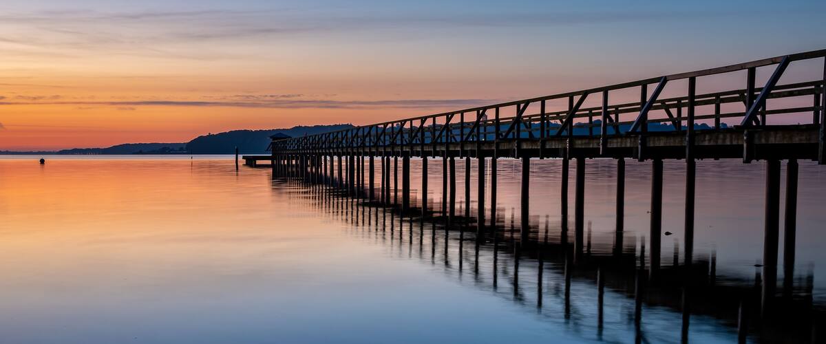 A pier extending into calm water at sunset.