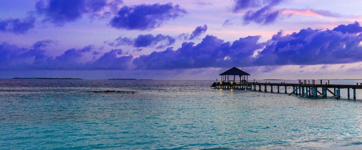 A pier extending into a turquoise sea with a gazebo at the end.