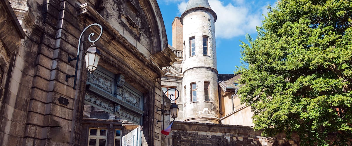 A historic building with ornate architecture, a tower, and a flag.