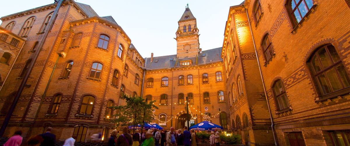 A historic courtyard with brick buildings, a tower, and people walking.