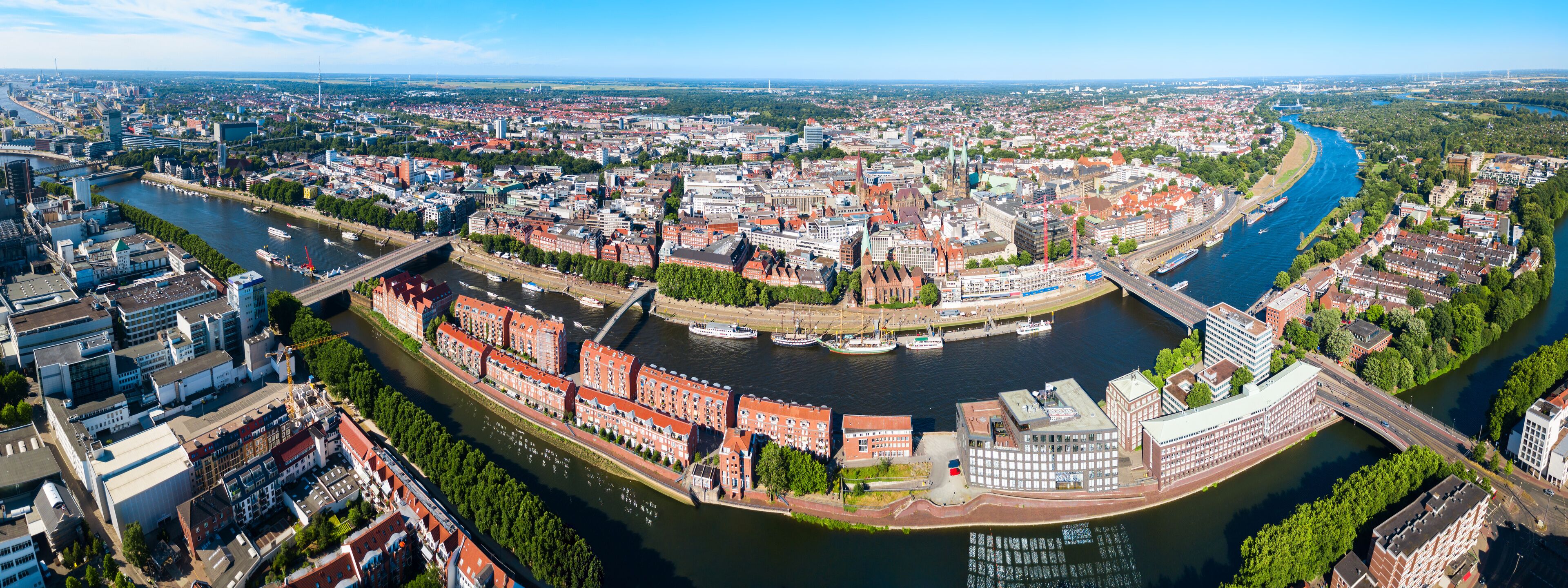 A panoramic view of a city with a river, historic buildings, and a modern bridge.