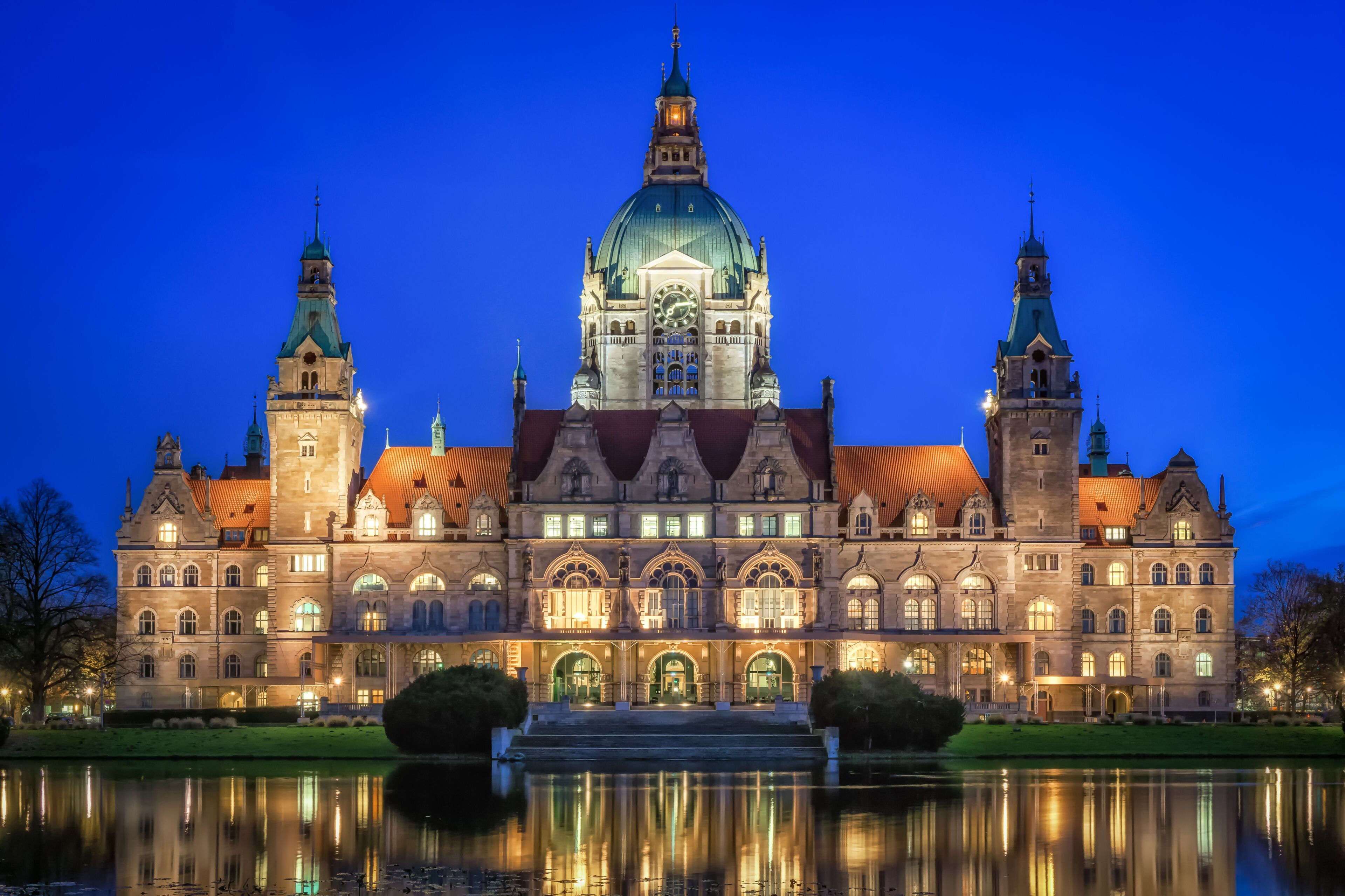 A grand historic building with a prominent dome and twin towers, reflecting in a calm body of water.
