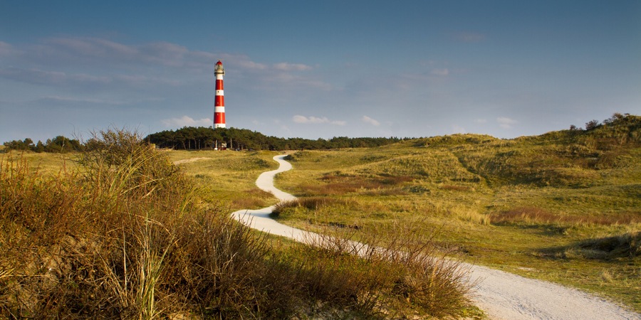 Path leading through the dunes towards vuurtoren, lighthouse of Ameland