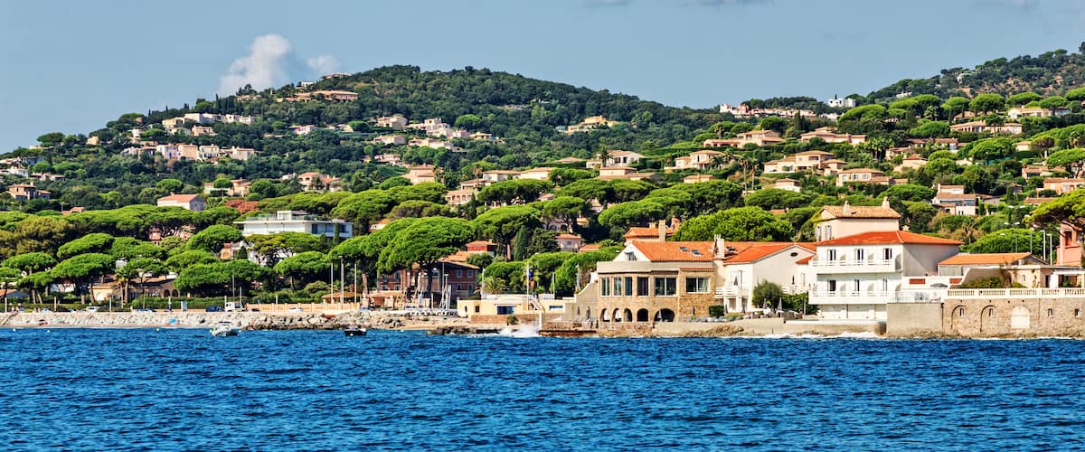 A coastal town with buildings on a hillside, a rocky shoreline, and the sea.