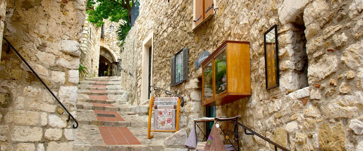 A narrow stone staircase in a historic town with a signboard and a small shop.