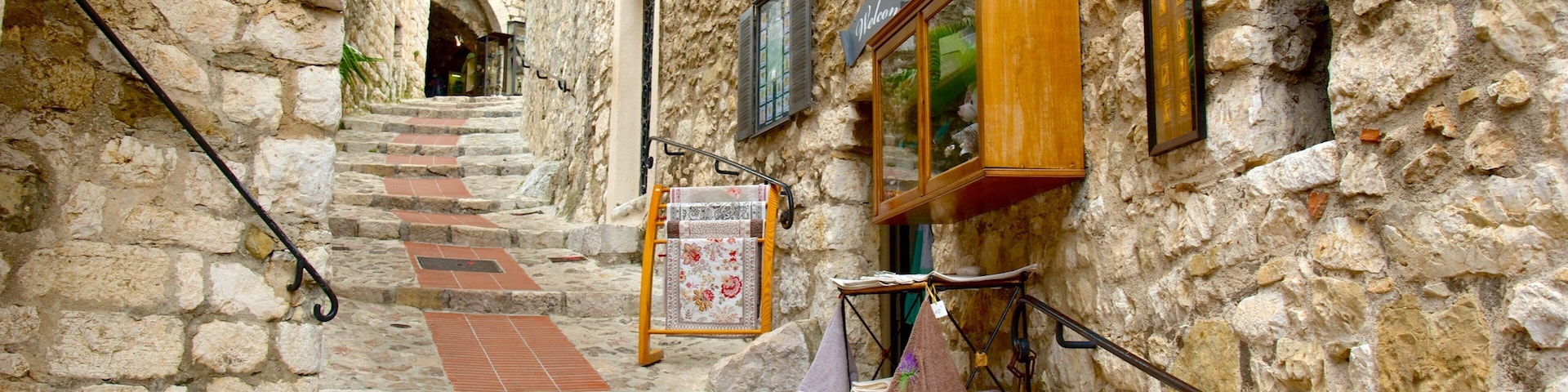 A narrow stone staircase in a historic town with a signboard and a small shop.