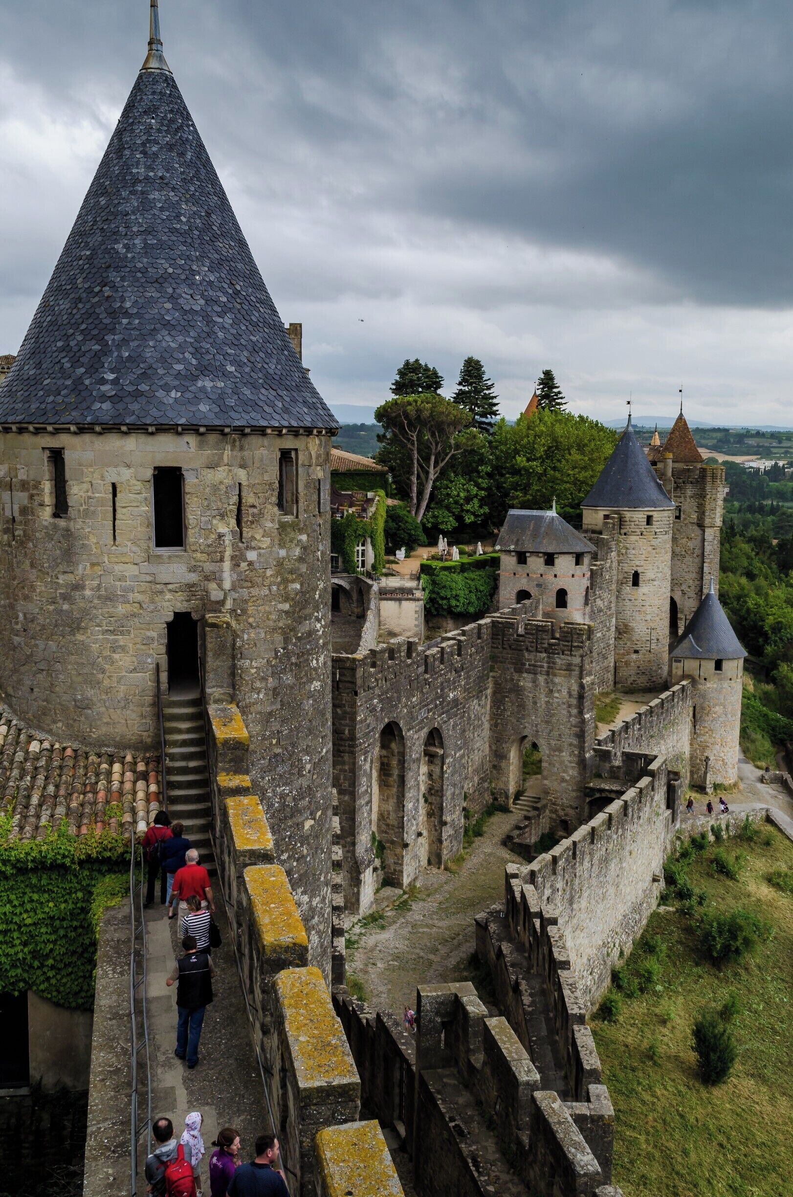 A historic castle with a conical tower, stone walls, and a surrounding moat.