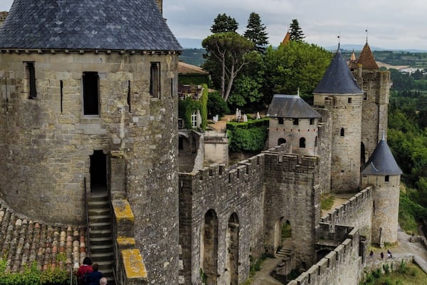 A historic castle with a conical tower, stone walls, and a surrounding moat.