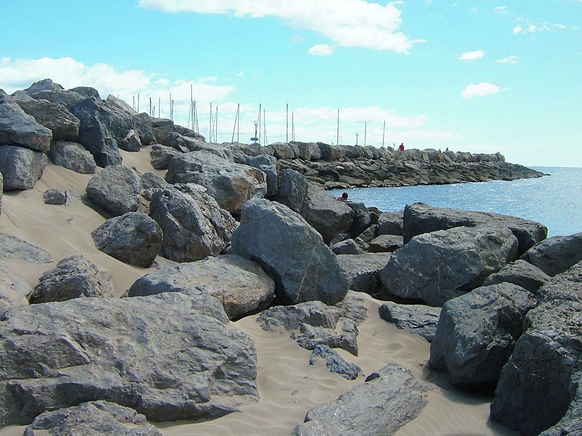 Una playa rocosa con grandes rocas y un cielo azul despejado.