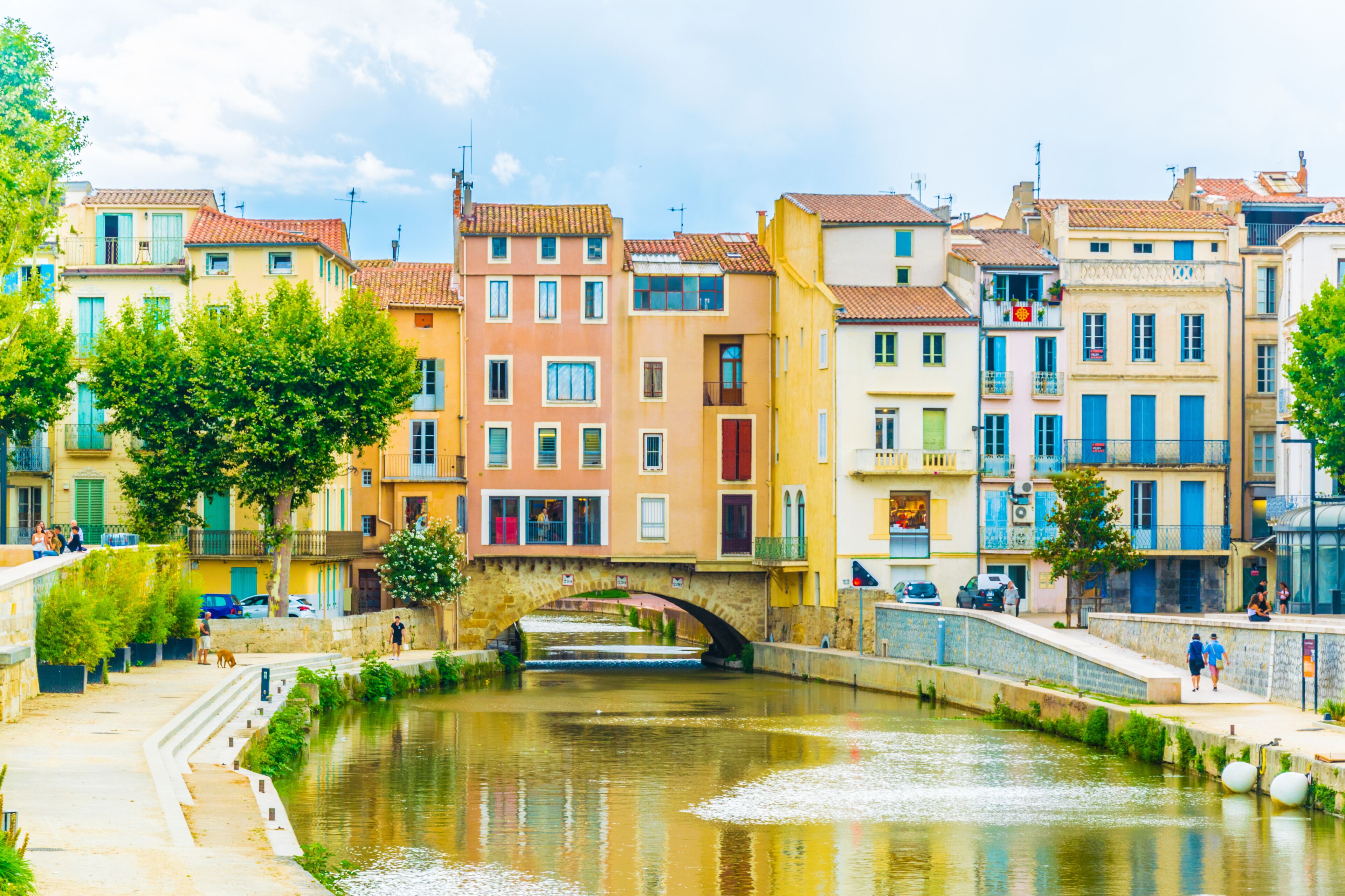 A canal with a stone bridge, colorful buildings, and a clear sky.