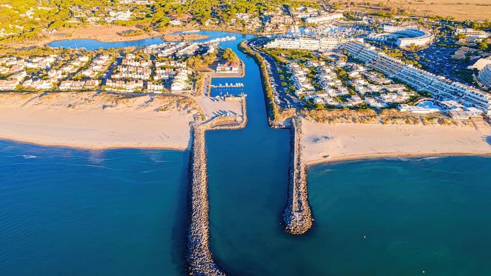 A coastal town with a marina, a lighthouse, and a river leading to the sea.