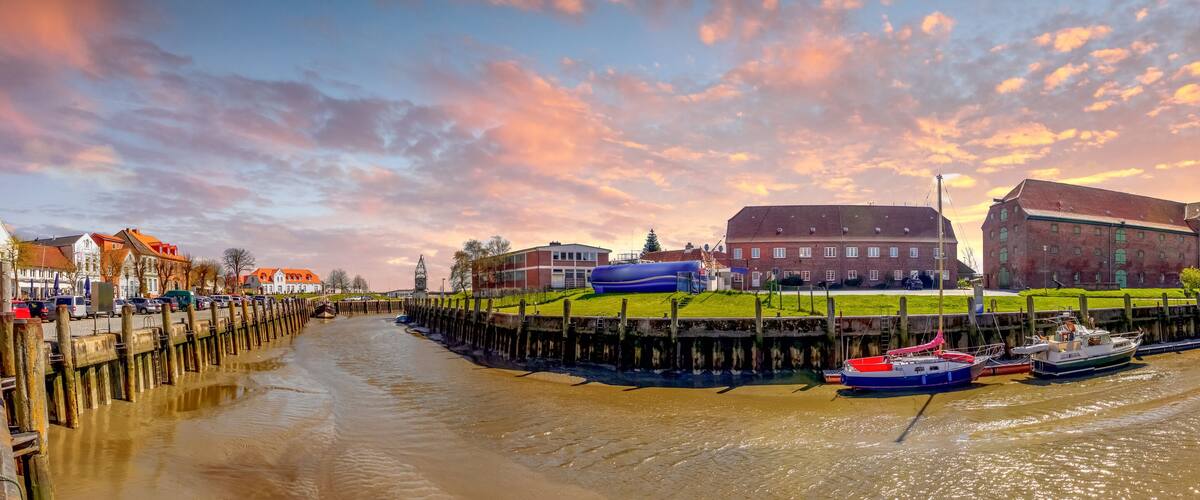 A canal with boats, a large building, and a sunset sky.