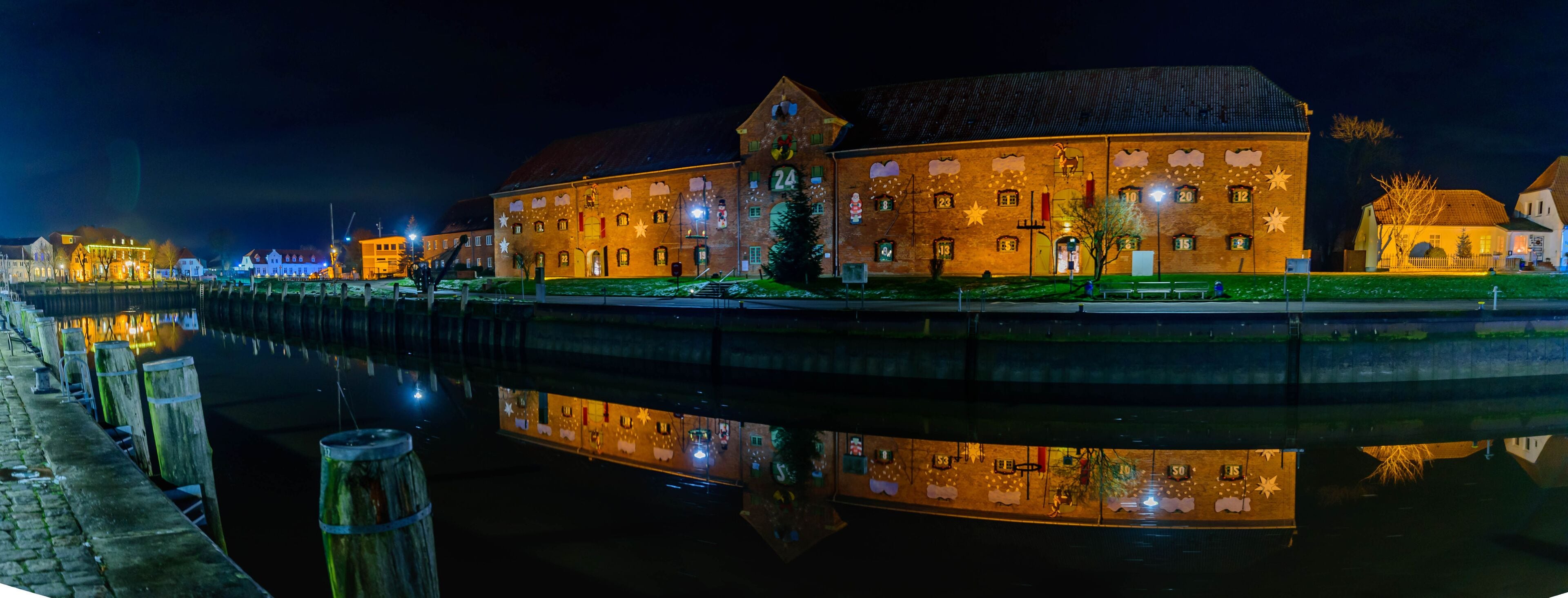 Panorama with view of the harbor with the famous Christmas market on two floors in the historic warehouse on the port of Toenning, Schleswig-Holstein, Germany.