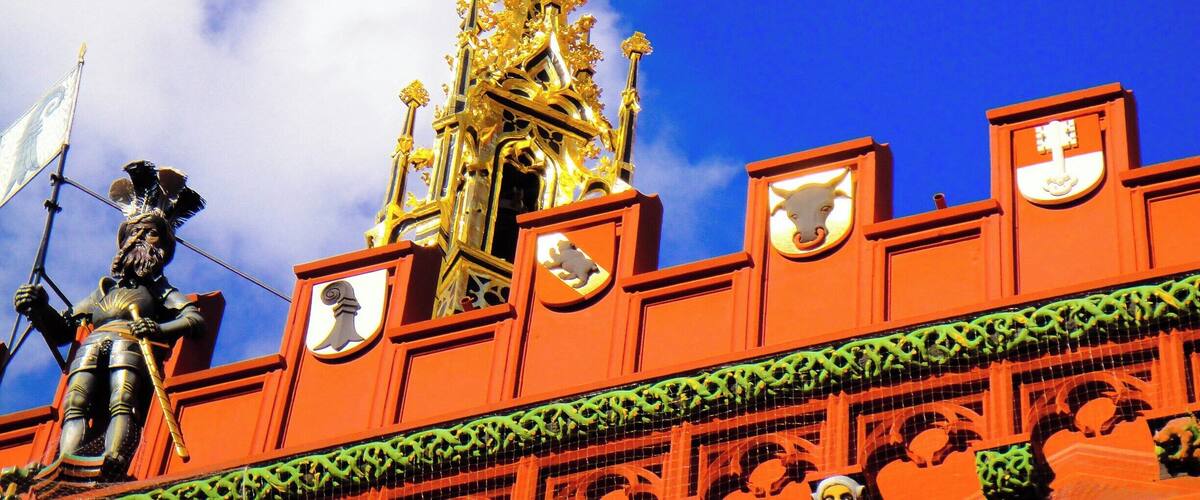 A golden spire atop a red building with a statue of a figure holding a flag.